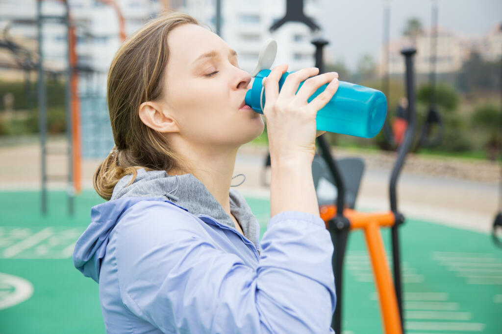 a lady drinking water from a good plastic water bottle